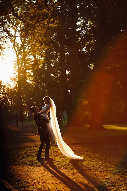 Sol de verão à noite faz uma auréola em torno do lindo casal de noivos