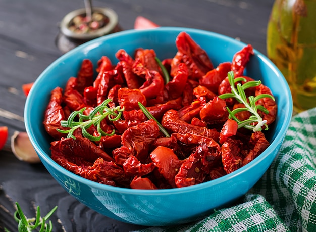 Foto grátis sol secou tomates com ervas e alho em uma tigela na mesa de madeira. comida italiana.