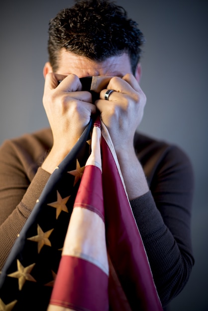 Foto grátis soldado aposentado, limpando as lágrimas com a bandeira dos estados unidos