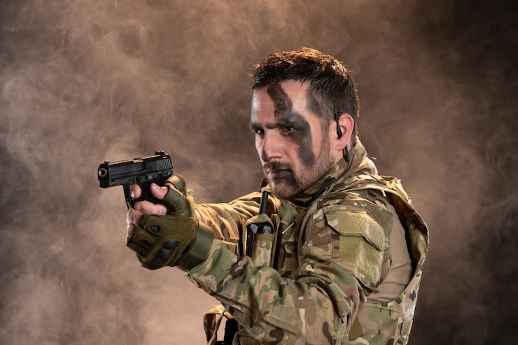 Foto grátis soldado do sexo masculino camuflado apontando a arma na parede escura esfumaçada