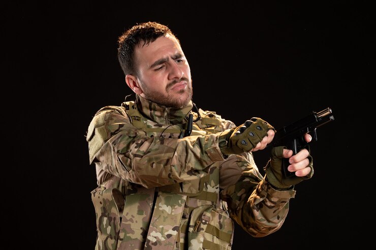 Foto grátis soldado do sexo masculino camuflado recarregando a arma na parede preta