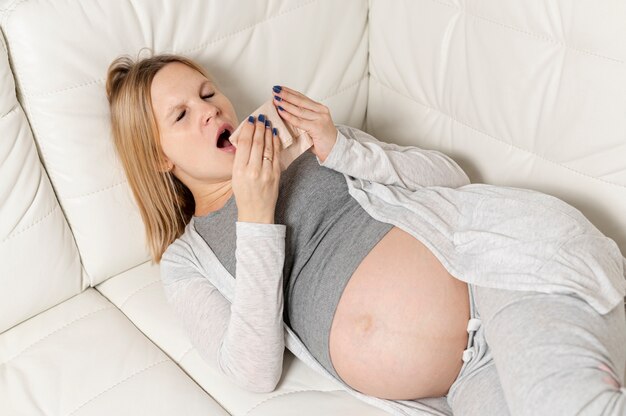 Sonolenta mulher grávida sentada no sofá