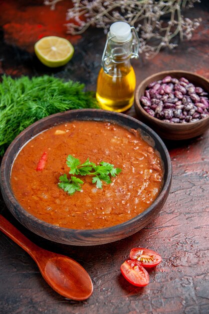 Sopa clássica de tomate em uma tigela de feijão marrom e garrafa de óleo de colher na mesa de cores diferentes