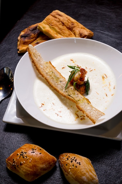 Sopa cremosa de frutos do mar camarão bolachas pãezinhos açafrão vista lateral