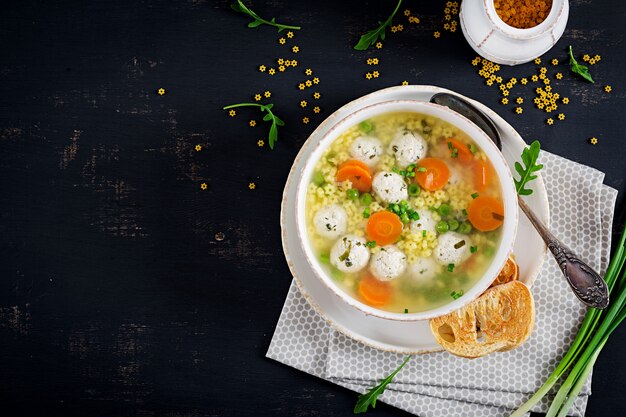 Sopa de almôndega italiana e massa Stelline em tigela na mesa preta.