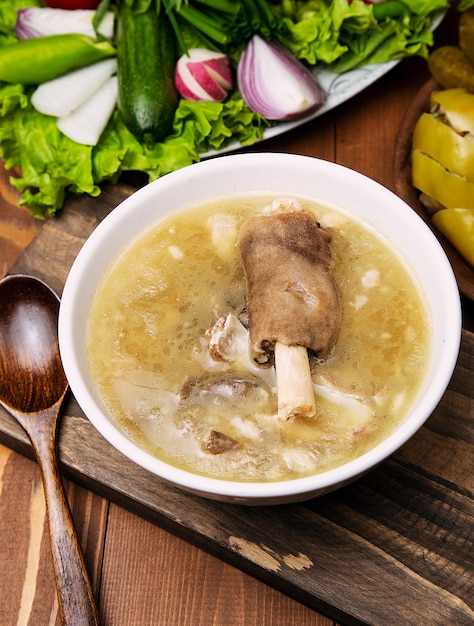 Sopa de carne de borrego com um pedaço de carne, molho de tomate e cebola, sumakh.