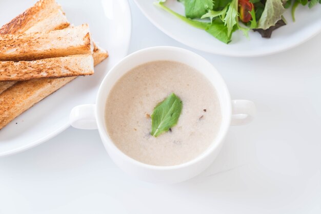 Sopa de cogumelos e pão em copo de cerâmica branca