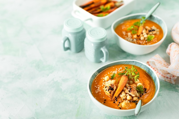 Sopa de creme de abóbora Sopa de puré de abóbora e cenoura com grão de bico e quinoa sobre fundo verde Cozinha vegetariana Receitas veganas