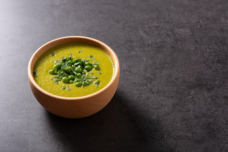 Foto grátis sopa de ervilha verde em uma tigela sobre fundo de ardósia preta