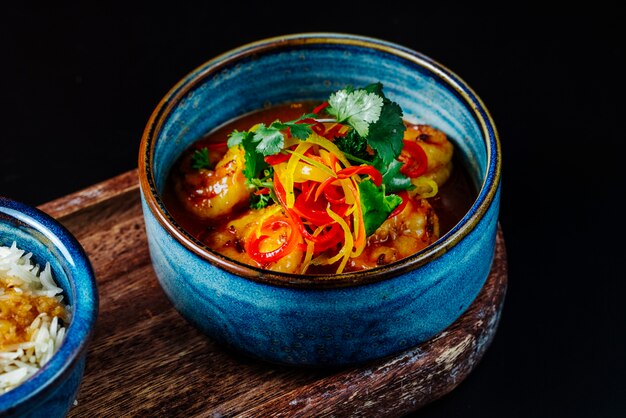 Sopa de frutos do mar com vista lateral em uma tigela azul em cima da mesa