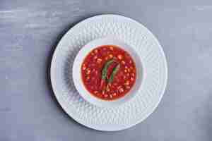 Foto grátis sopa de milho com molho de tomate em uma tigela branca.