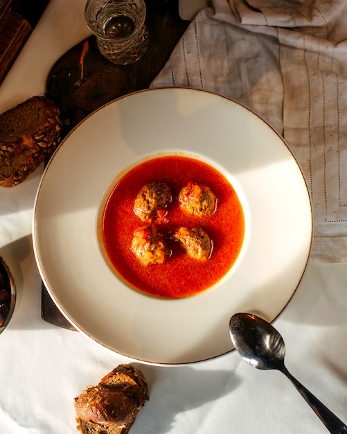 Sopa de vista superior com tomate de carne, juntamente com fatias de pão no chão branco