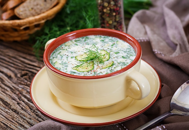 Sopa fria de iogurte de verão com ovo, pepino e endro na mesa de madeira