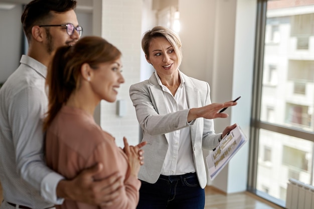 Sorridente agente imobiliário conversando com um casal interessado em comprar uma nova casa