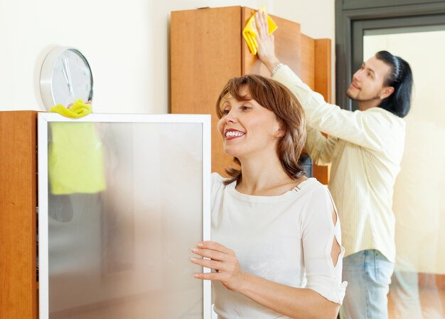 Sorridente casal de limpeza em casa