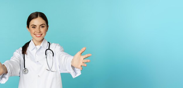 Sorridente e amigável médica estagiária de saúde alcançando mãos convidando abraços ou recebendo i