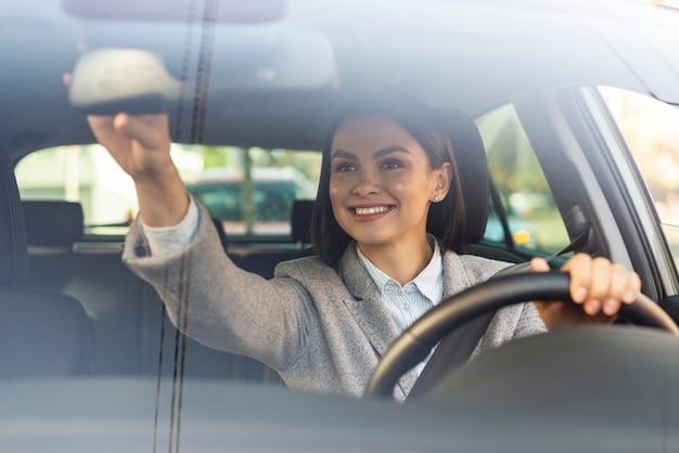 Foto grátis sorridente empresária ajustando o espelho retrovisor do carro