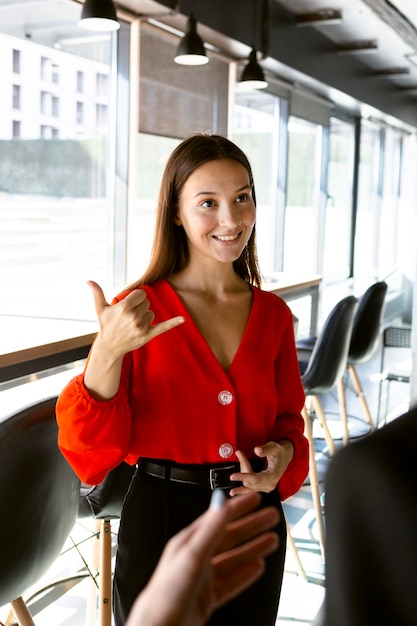 Foto grátis sorridente empresária usando linguagem de sinais no trabalho