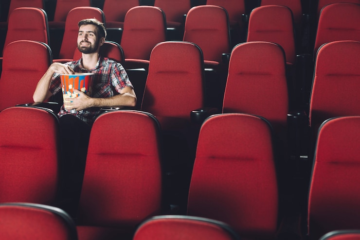 Foto grátis sorridente homem comendo pipoca no cinema