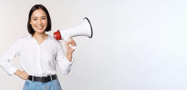 Sorridente jovem asiática posando com o conceito de megafone de anúncio de notícias e informações standin