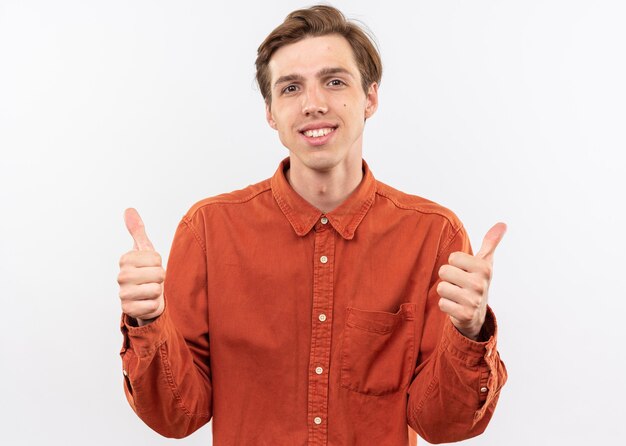 sorridente jovem bonito vestindo camisa vermelha mostrando os polegares para cima isolado na parede branca