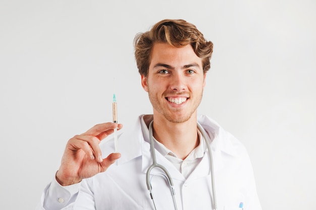 Sorridente jovem médico com seringa