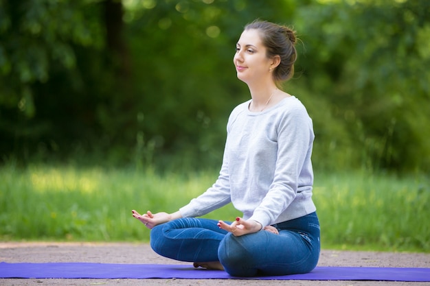 Sorridente jovem meditando no parque