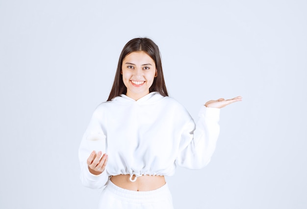 Sorridente jovem modelo segurando um copo de plástico.