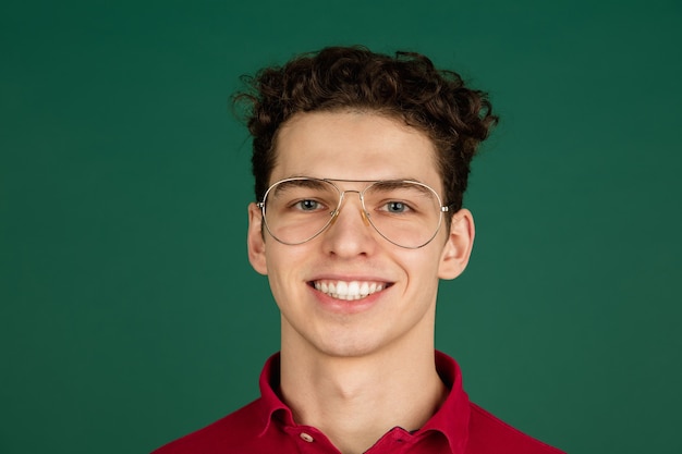 Foto grátis sorridente. retrato de homem bonito caucasiano isolado em um fundo verde com copyspace.