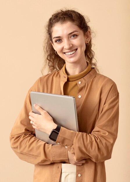 Sorridente senhora de cabelos cacheados segurando um laptop