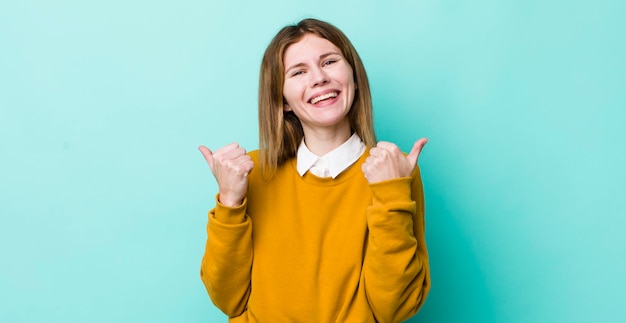 Sorrindo alegremente e parecendo feliz sentindo-se despreocupado e positivo com os dois polegares para cima