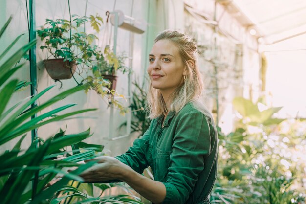 Sorrindo, atraente, mulher jovem, trabalhando, em, a, plantas, berçário