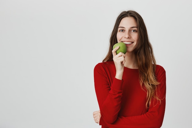 Sorrindo atraente mulher saudável comer maçã verde