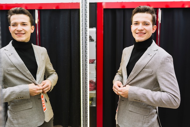 Sorrindo, bonito, homem jovem, tentando, casaco, frente, espelho