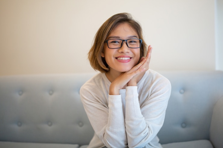 Foto grátis sorrindo, bonito, mulher jovem, sentar sofá, e, posar, câmera