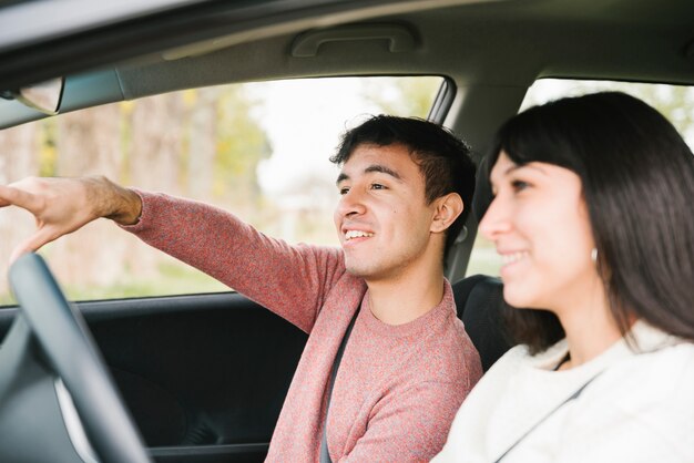 Sorrindo casal apontando e olhando em frente no carro