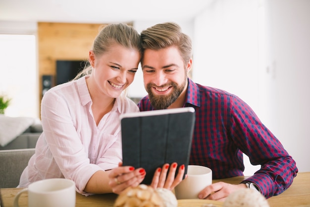 Foto grátis sorrindo casal com tablete na mesa