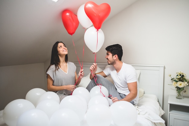 Sorrindo casal segurando balões vermelhos e brancos