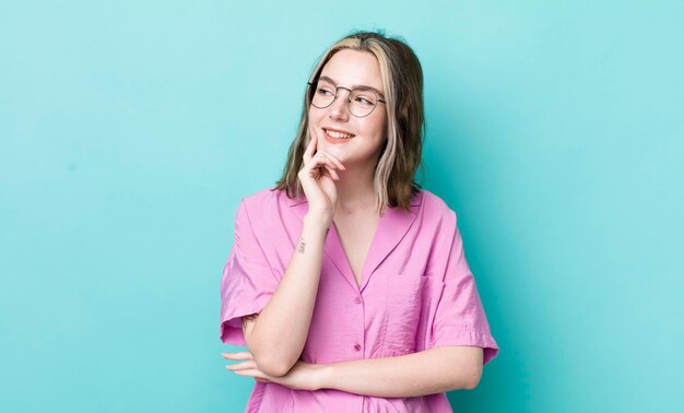 Sorrindo com uma expressão feliz e confiante com a mão no queixo pensando e olhando para o lado