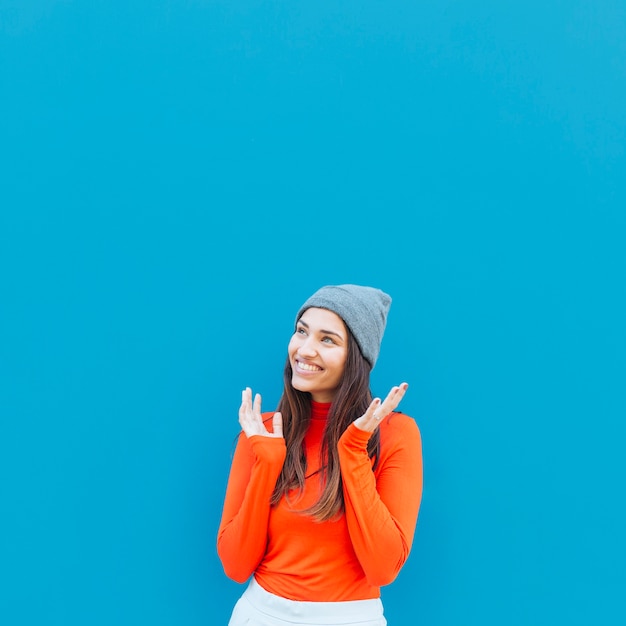 Sorrindo dia sonhando mulher olhando para longe contra o fundo azul