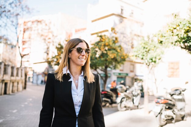 Sorrindo, elegante, mulher jovem, com, óculos de sol, ligado, rua