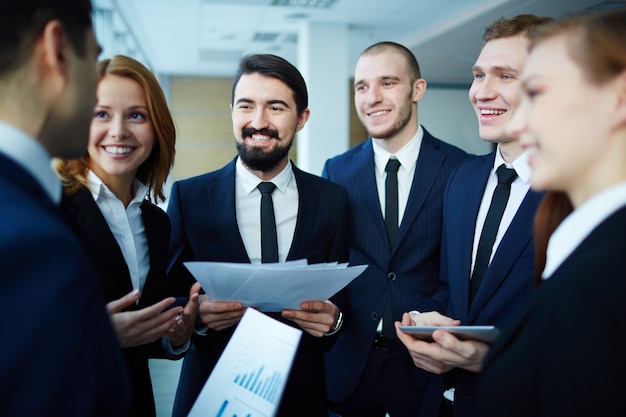 Sorrindo executivo segurando alguns documentos com colegas de trabalho