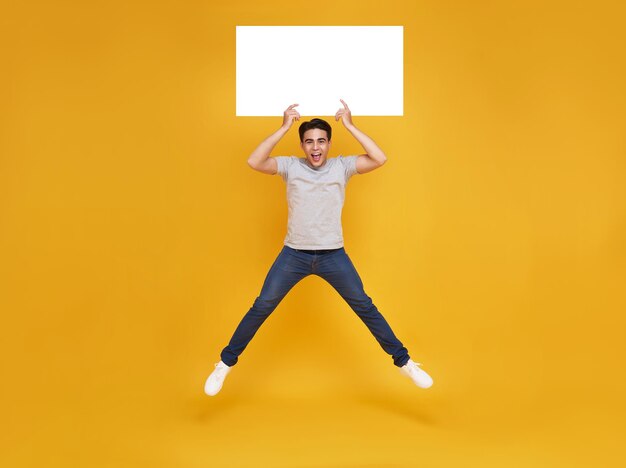Sorrindo feliz homem asiático pulando e segurando bolhas de fala em branco no fundo amarelo anunciam o conceito de anúncio