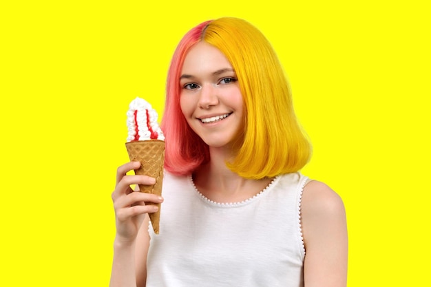 Sorrindo feliz linda adolescente modelo com sorvete no cone de waffle sobre fundo amarelo do estúdio. conceito de verão, comida, beleza e moda Foto Premium