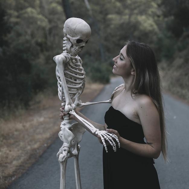 Foto grátis sorrindo, femininas, segurando, artificial, esqueleto, de, posição homem, ligado, estrada