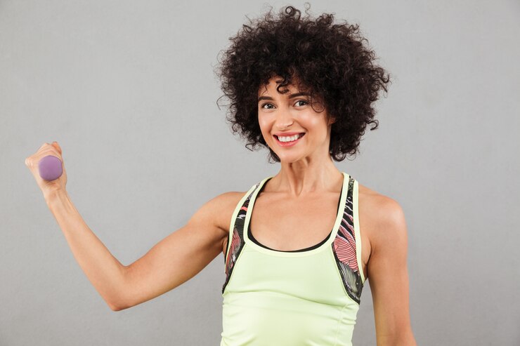 Foto grátis sorrindo fitness mulher fazendo exercício com halteres em estúdio