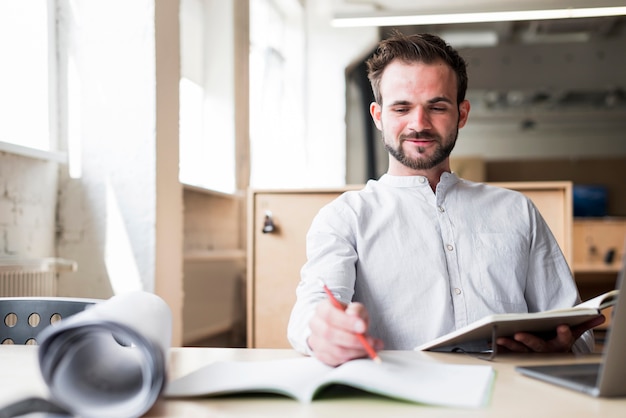 Foto grátis sorrindo, homem jovem, sentando, ligado, cadeira, trabalhando, em, escritório