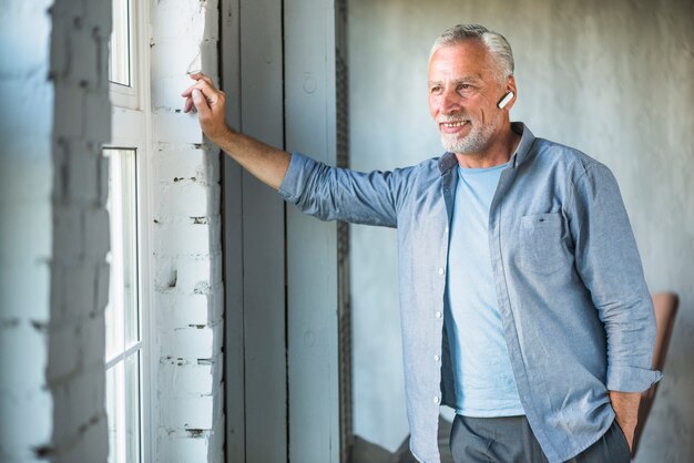 Foto grátis sorrindo, homem sênior, com, sem fios, bluetooth, olhar janela