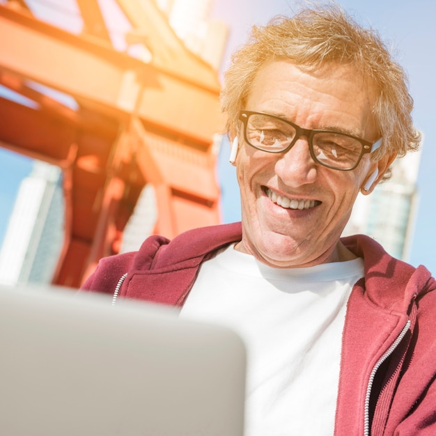 Foto grátis sorrindo, homem sênior, óculos desgastando, usando computador portátil