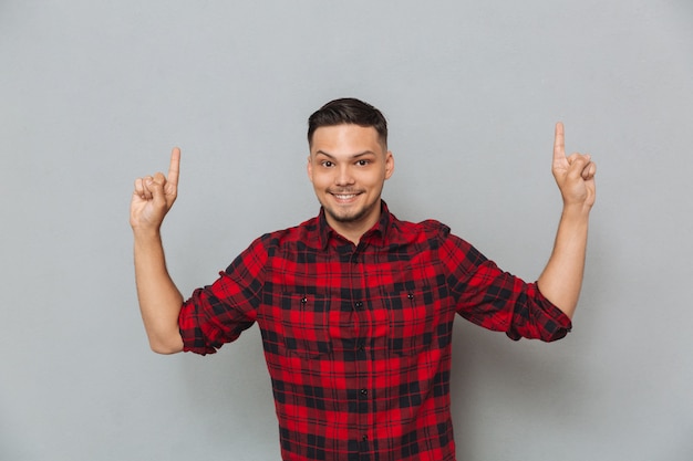 Foto grátis sorrindo jovem apontando.